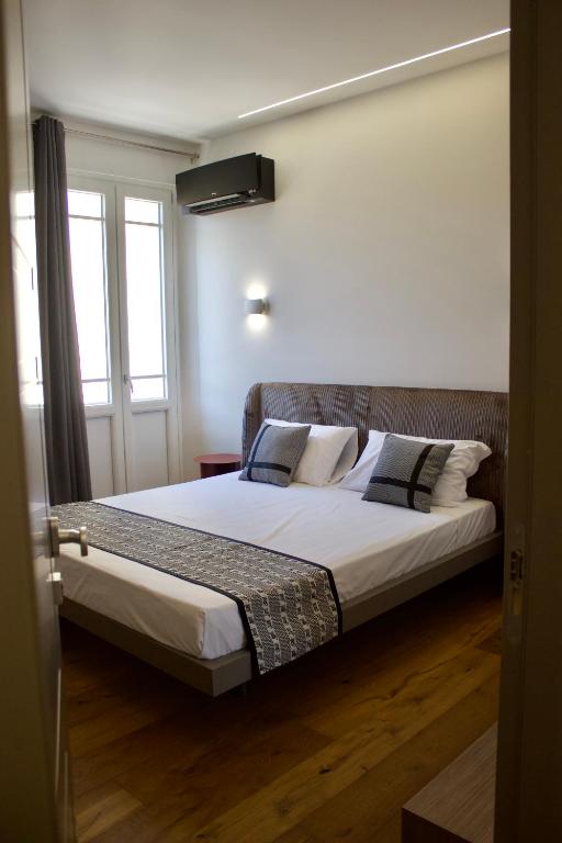 a bedroom with a bed with white sheets and pillows at Luxenti Luxury Rooms in Cagliari