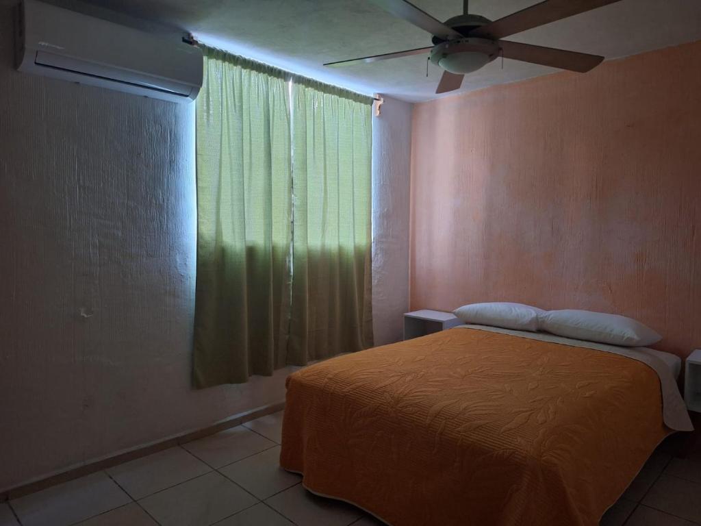 a bedroom with a bed and a window with a fan at Departamento cerca de la playa in Puerto Vallarta