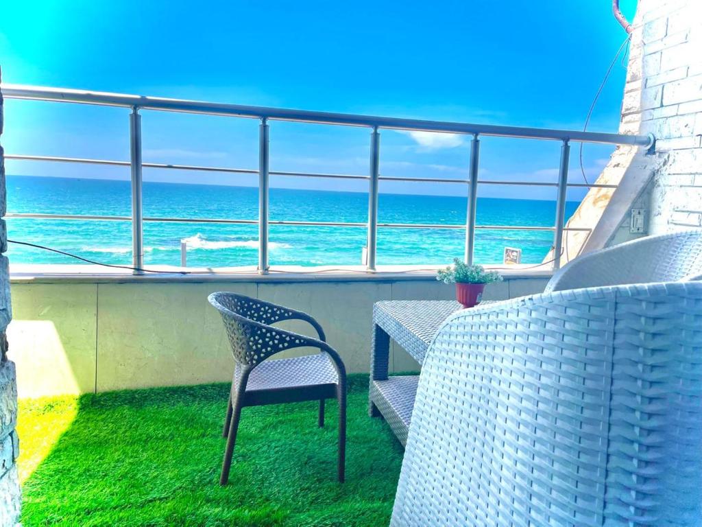 a balcony with a table and chairs and the ocean at Luxurious Beachfront Apartment in Alexandria