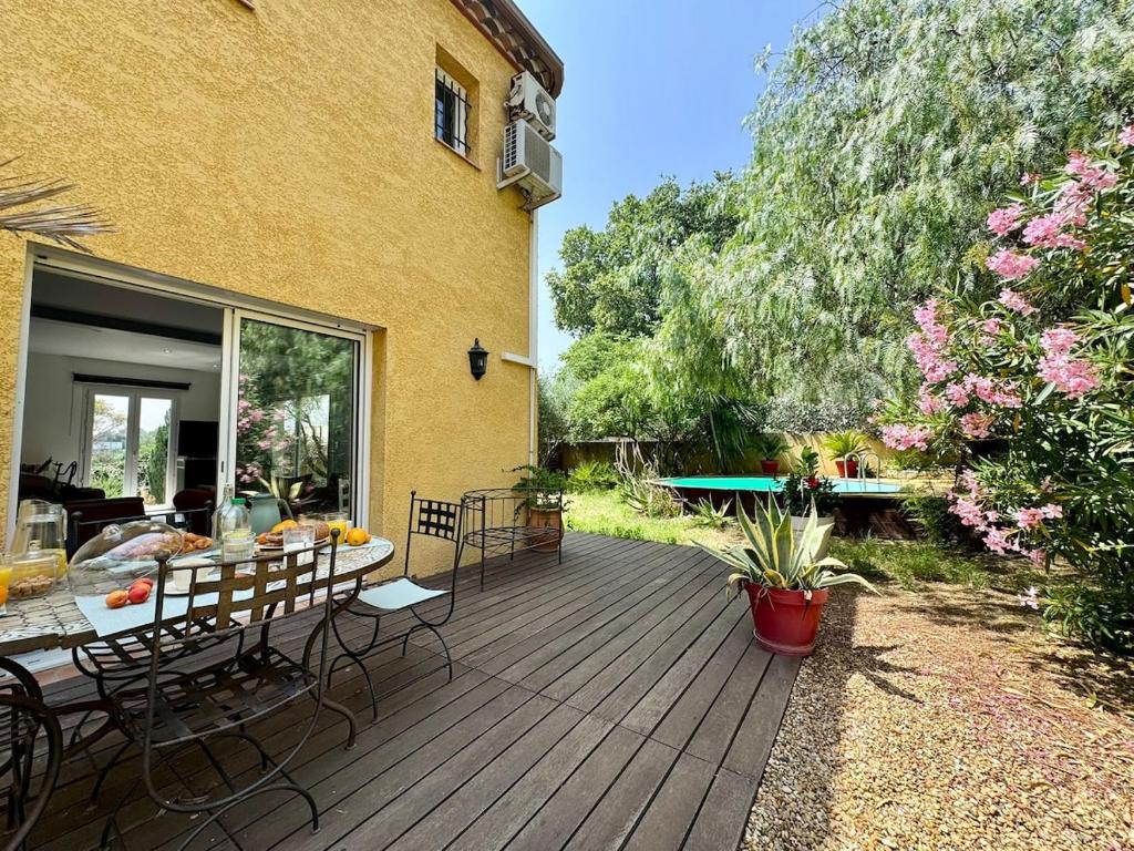 una terrazza in legno con tavolo e sedie. di Maison Occitane avec Piscine a Béziers