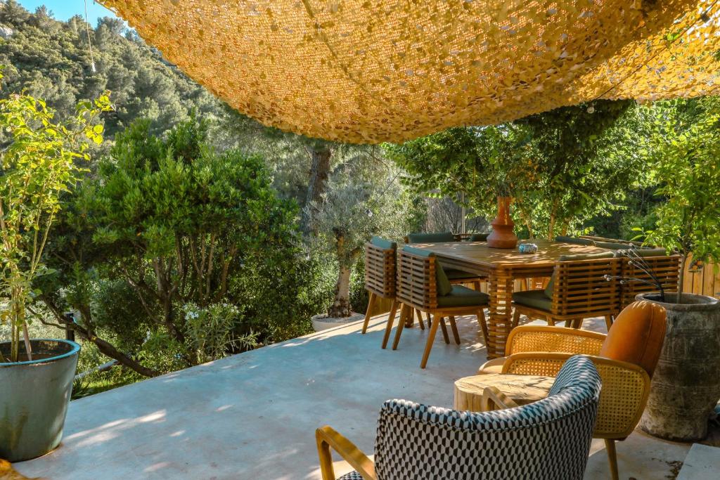 eine Terrasse mit einem Tisch, Stühlen und Bäumen in der Unterkunft Villa art de vivre & absolute calm Baux de Provence in Les Baux-de-Provence