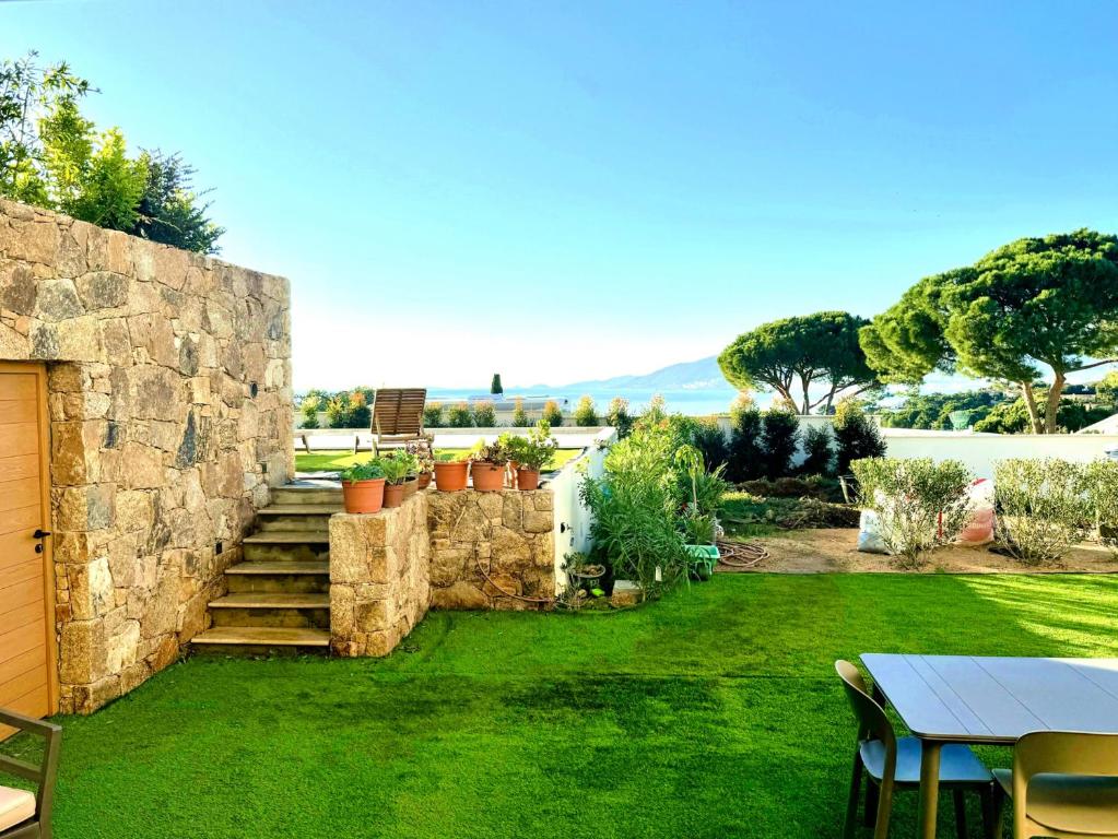 a garden with a stone wall and a table at Domaine LUMISTELLA 2 in Porticcio