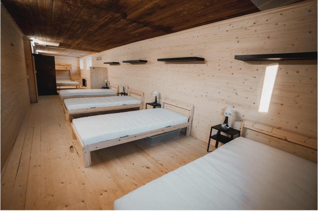 three beds in a room with wooden walls at VitaNorse AB in Älglund