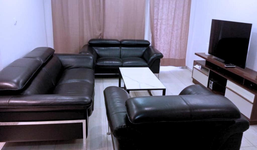 un soggiorno con mobili in pelle nera e una TV a schermo piatto di Le Conviviall a Yaoundé