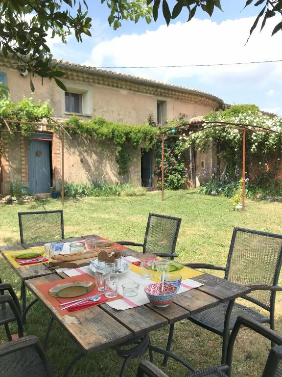 - une table en bois avec des chaises dans la cour dans l'établissement Le Mas de Loume, à Sault