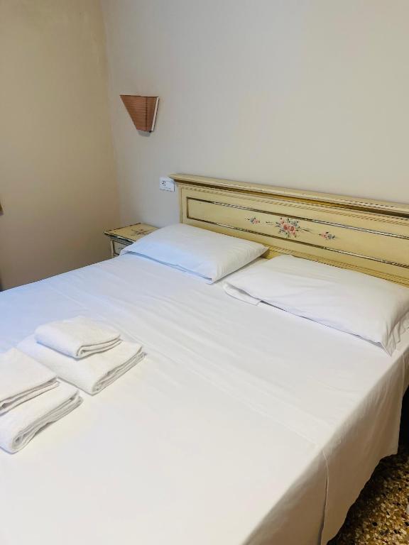 a white bed with two white towels on it at Santa croce 241 in Venice