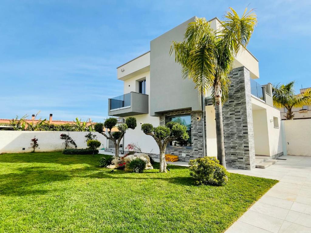 a house with a palm tree in a yard at Villa Canepa in Marsala