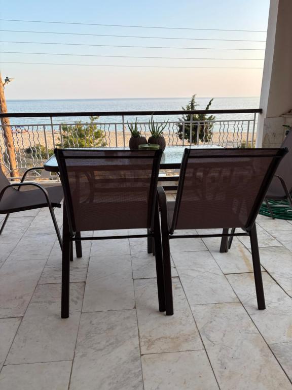 two chairs and a table on a balcony with the beach at Aether House Αιθήρ in Toroni
