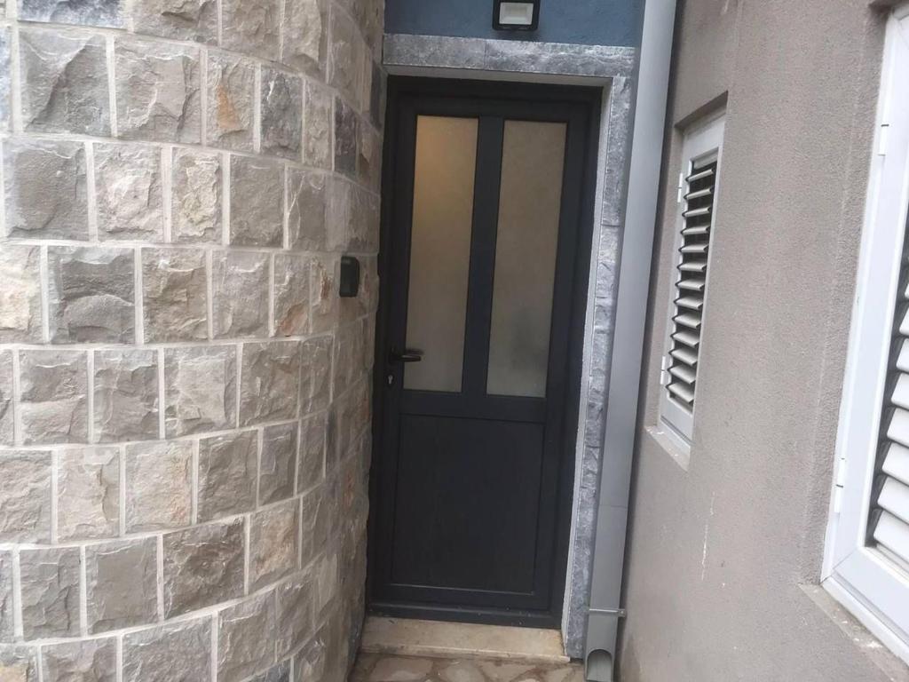 a black door in a brick wall at Compact Apartments for Solo Travelers in Igalo