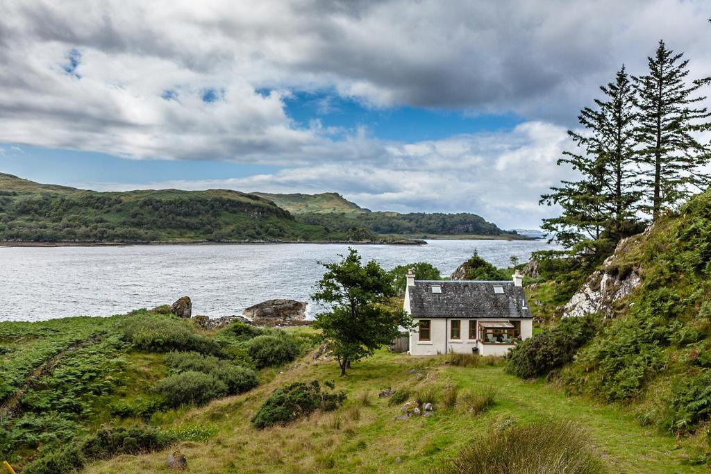 a house on a hill next to a body of water at Tigh Beg Croft in Lerags