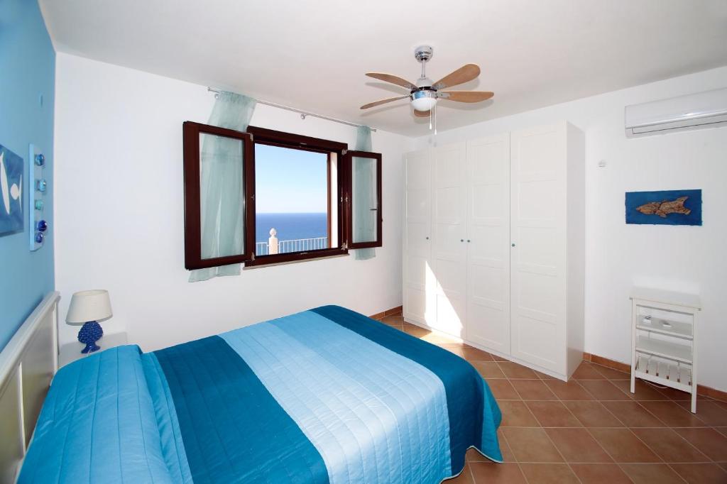 une chambre avec un lit bleu et une fenêtre dans l'établissement Villa DAMMUSO by Local House - private villa infinity pool & seaview, à Santo Stefano di Camastra