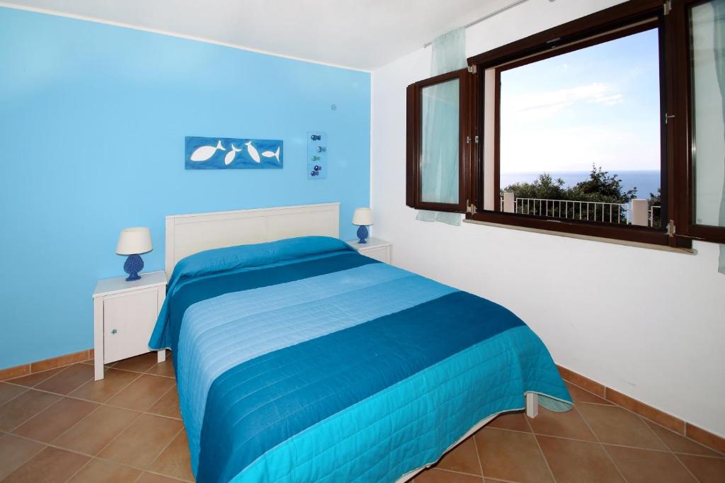 - une chambre bleue et blanche avec un lit et une fenêtre dans l'établissement Villa DAMMUSO by Local House - private villa infinity pool & seaview, à Santo Stefano di Camastra