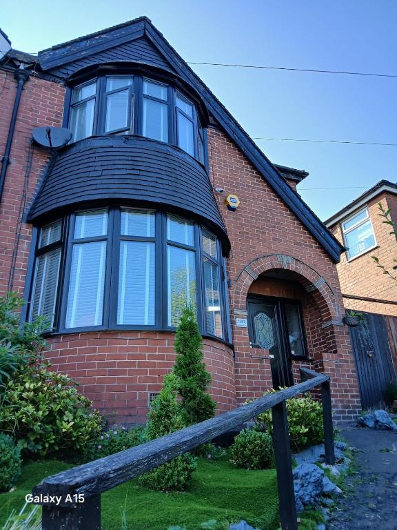 a red brick house with a large window at 2 bedroomed homely house in Manchester