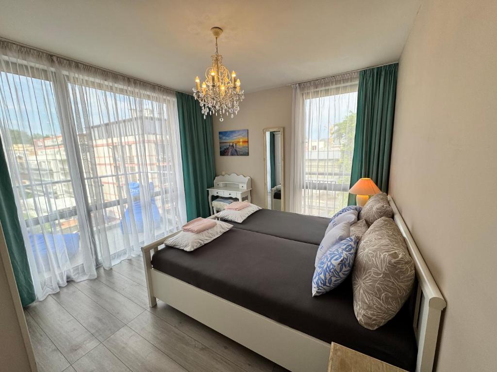 a bedroom with a bed with a chandelier and windows at Apartment B48 in Tarsis Club Complex in Sunny Beach