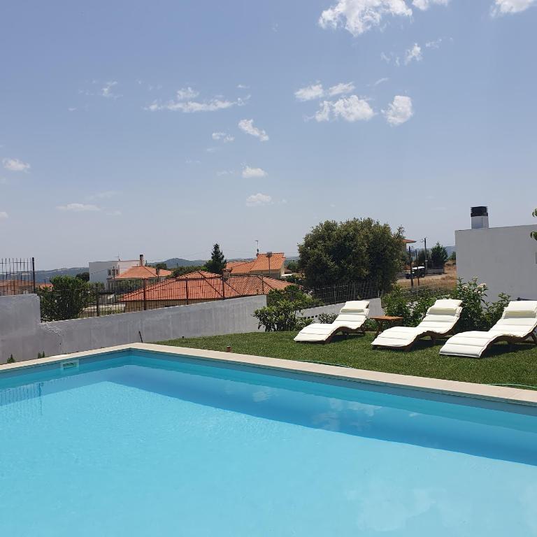 a swimming pool with two lounge chairs next to at Casa das Lagoas com piscina aquecida exclusiva in Bragança