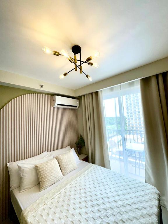 a bedroom with a bed with a ceiling fan and a window at Cloud Nine Poolview Condo Near Mactan Airport in Suba