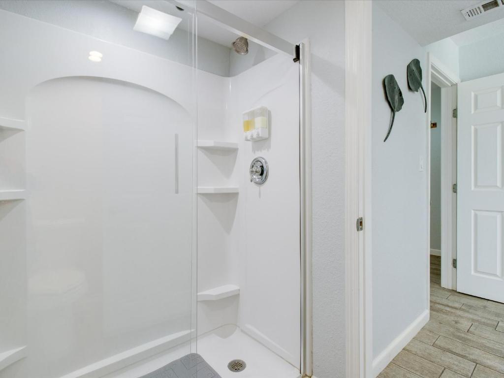 a white bathroom with a shower and a glass door at Bayfront Kontiki 107 in Rockport