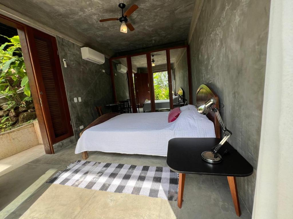 a bedroom with a bed and a table with a lamp at Suítes independentes - Praia Barra do Sahy in São Sebastião