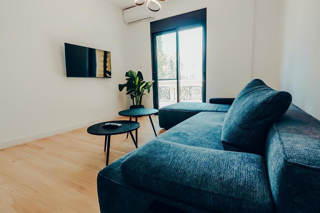 a living room with a blue couch and a tv at Dreamy Glyfada Apartment in Athens