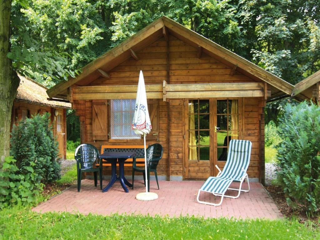 a cabin with a table and chairs and an umbrella at Blockhäuser am Fährsee, Templin in Templin