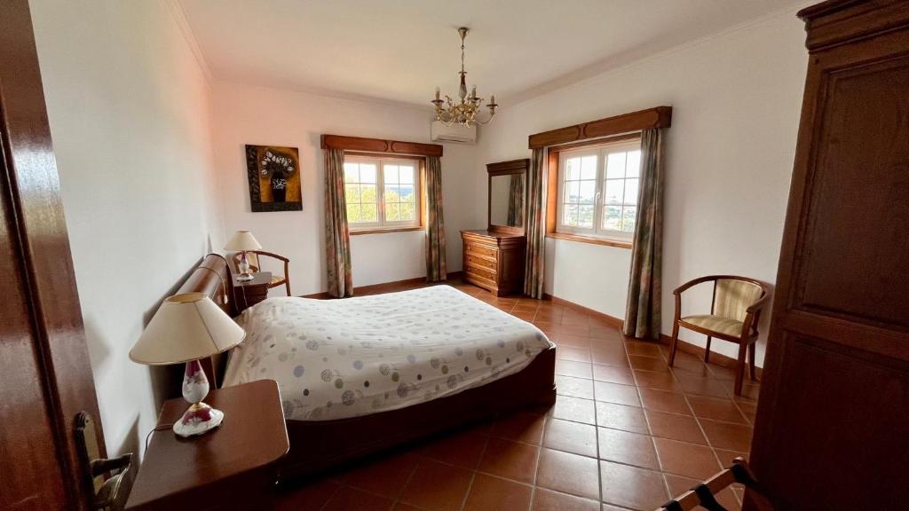 にあるCasa do Cabo Altoのベッドとテーブルと2つの窓がある寝室