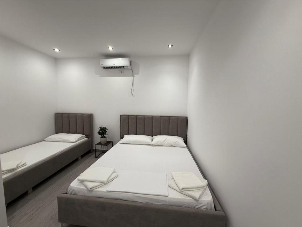 two beds in a room with white walls at Vacation rooms in Vlorë