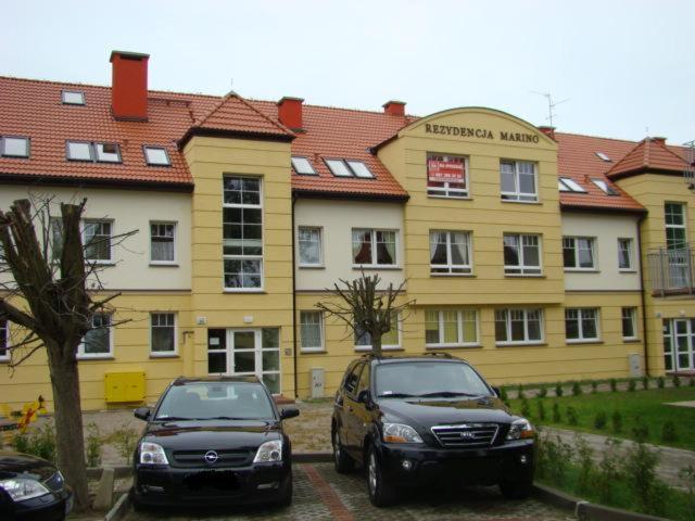 two cars parked in front of a yellow building at Apartment with Terrace in Rewal