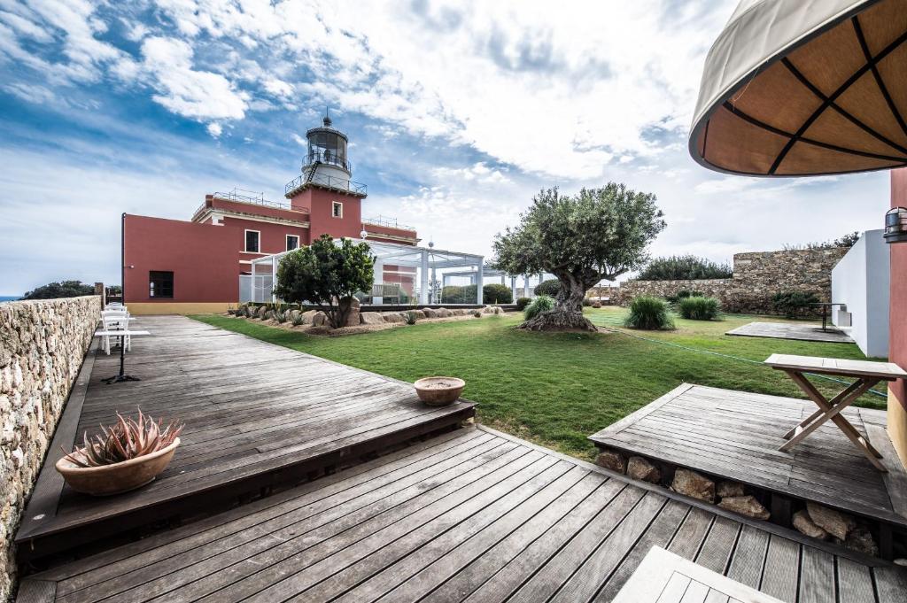 a wooden deck in front of a building with a lighthouse at Faro Capo Spartivento in Chia