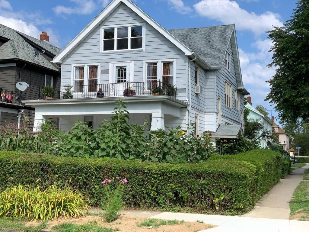 a white house with a balcony and bushes at The Paradise House steps from the Heart of Hertel in Buffalo