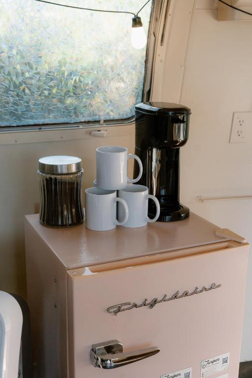 Un estante con tazas encima de un refrigerador. en The Juniper Ranch and Retreat, en Canyon Lake