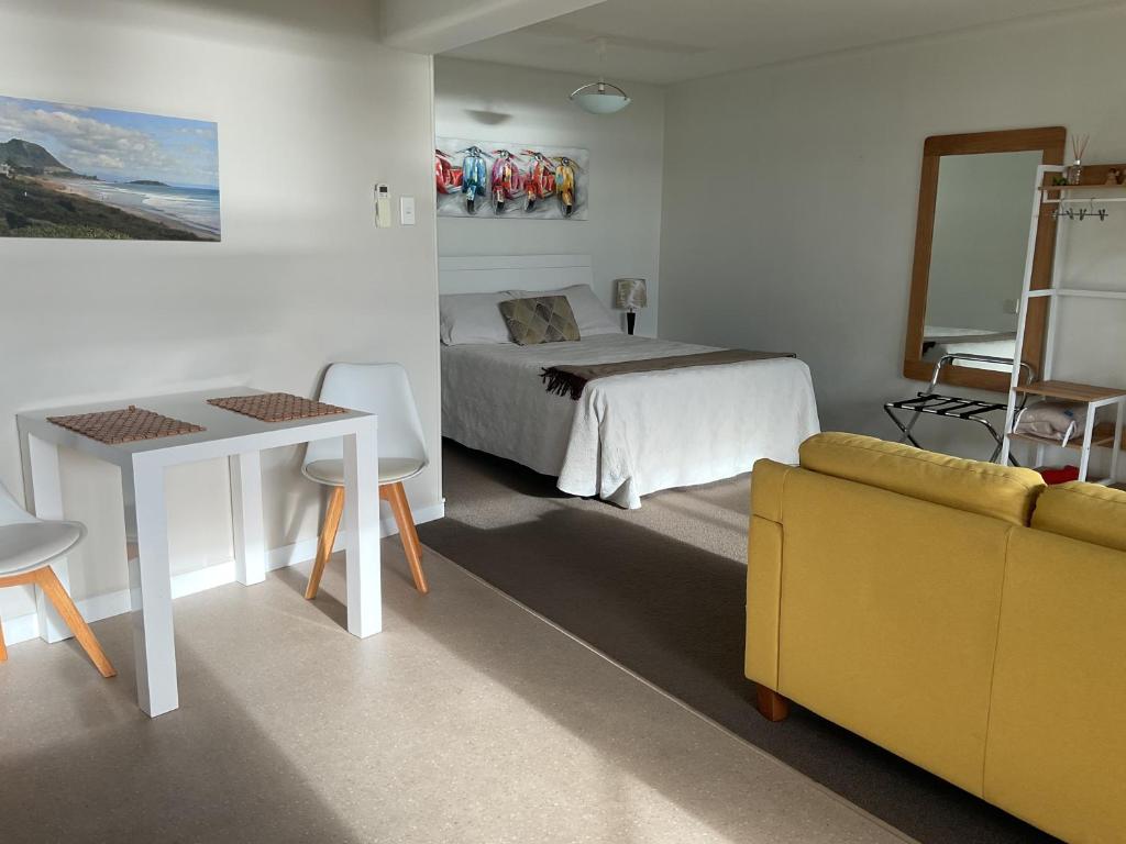 a bedroom with a bed and a table and a couch at Spacious Studio - Self Contained in Tauranga