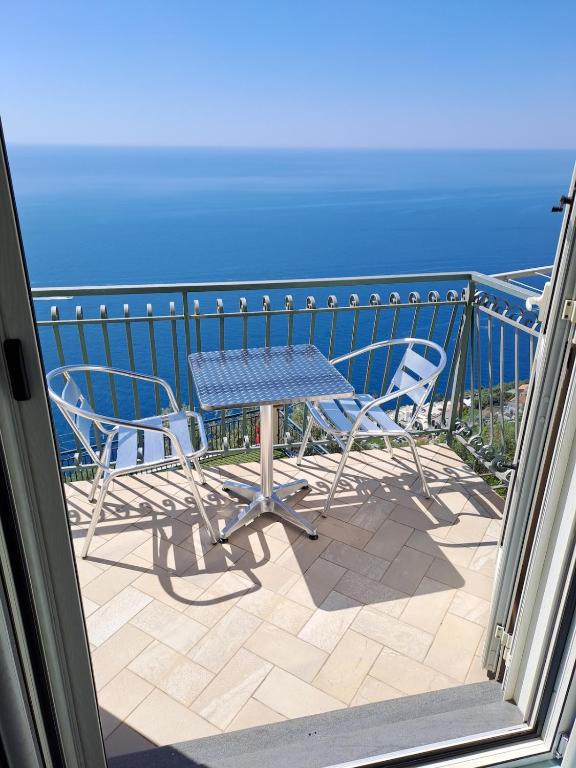 a table and chairs on a balcony with the ocean at Casa Belle Vue in Furore