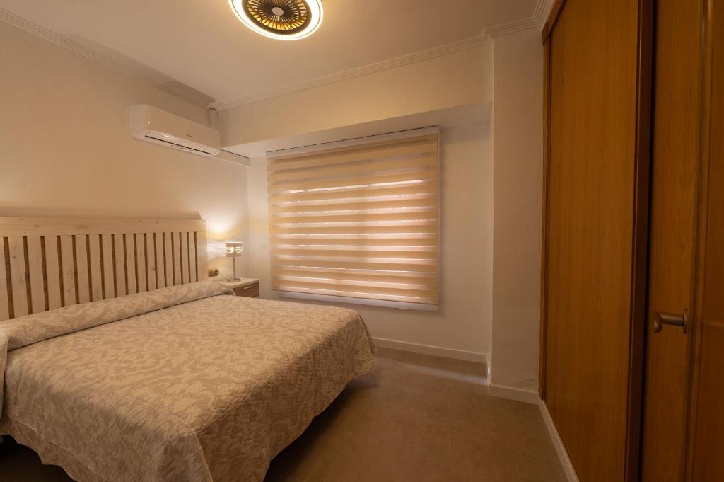 a bedroom with a bed and a window with blinds at Holiday Beach Centro in Santa Pola