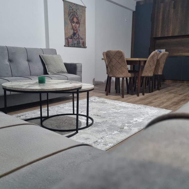 a living room with a couch and a table and chairs at Etno apartmemt in Prishtinë