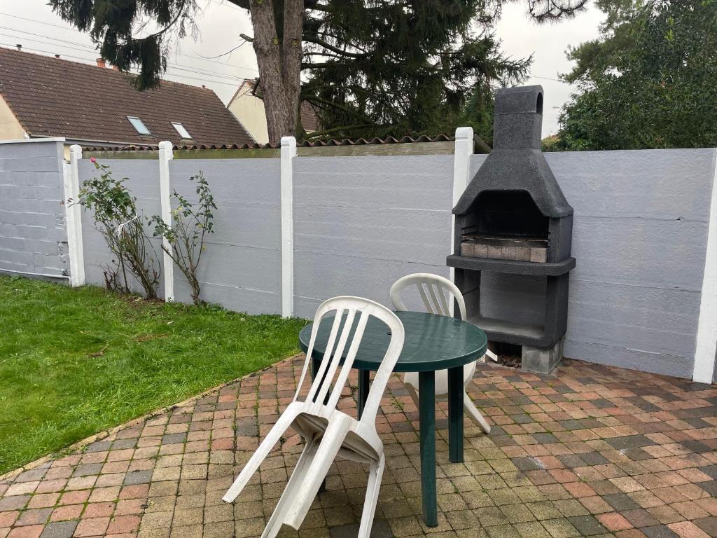 two chairs and a table and a grill in a backyard at Douai à proximité in Flers-en-Escribeus