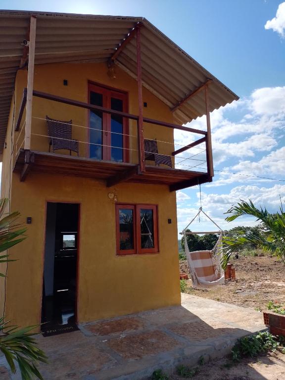 a yellow house with a balcony on top of it at Chalé Vista da Serra in Pedro II