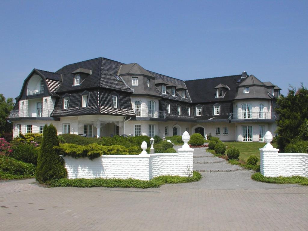 uma casa grande com uma cerca branca em frente em Stelinger Hof Hotel Münkel em Hanôver