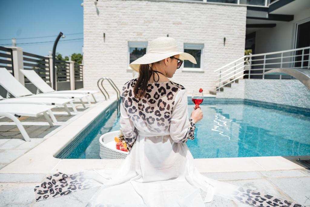 a woman holding a glass of wine next to a pool at Villa Blue Haven in Ulcinj