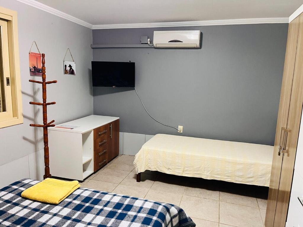 Un dormitorio pequeño con dos camas y un televisor. en Apzito Tri com garagem, en Porto Alegre