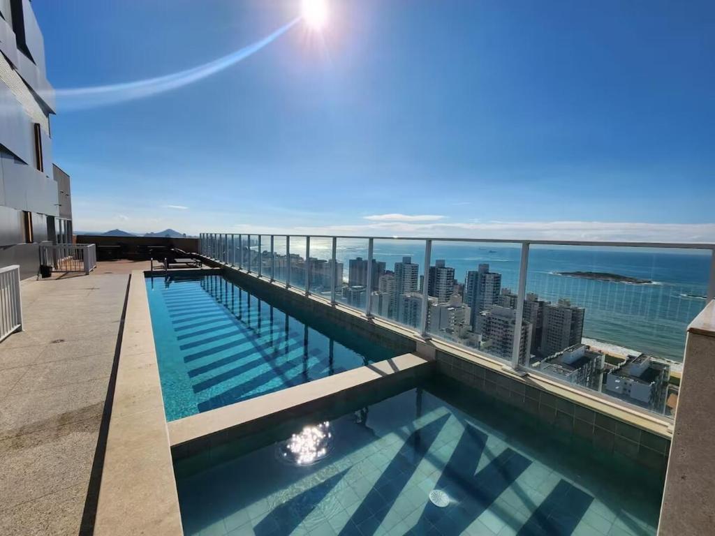 une piscine sur le toit d'un immeuble avec l'océan dans l'établissement Apartamento Pé na Areia com Piscina e Vista Mar ao lado do Itaparica Food Park, à Vila Velha