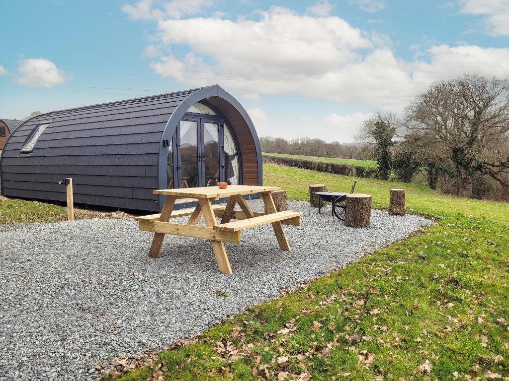 Una mesa de picnic frente a una carpa tipo domo con un banco. en Hayfield Haven-Uk40691, en Crowhurst