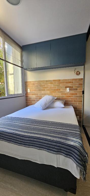 a bedroom with a large bed with a brick wall at Um lugar de charme e aconchego - Rosa! in Brasília
