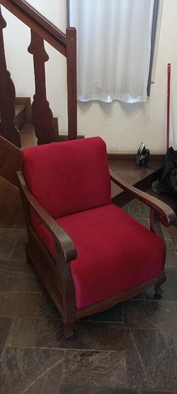 a red chair sitting in a room with a window at Surpreendente in Ouro Preto