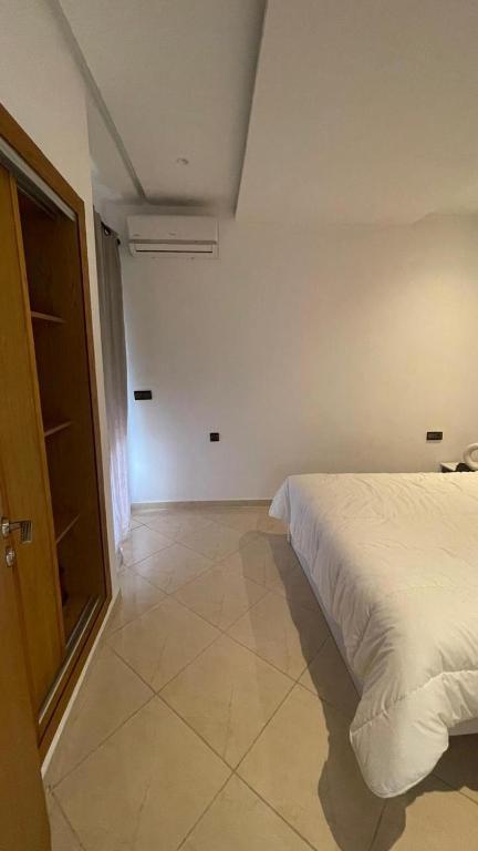 a bedroom with a white bed and a window at Cosy Appartement en plein centre ville in Kenitra