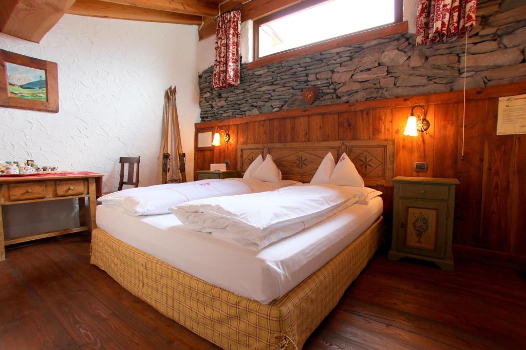 a bedroom with a large bed with a stone wall at Eco Chalet Maison Dominique in Challand Saint Anselme