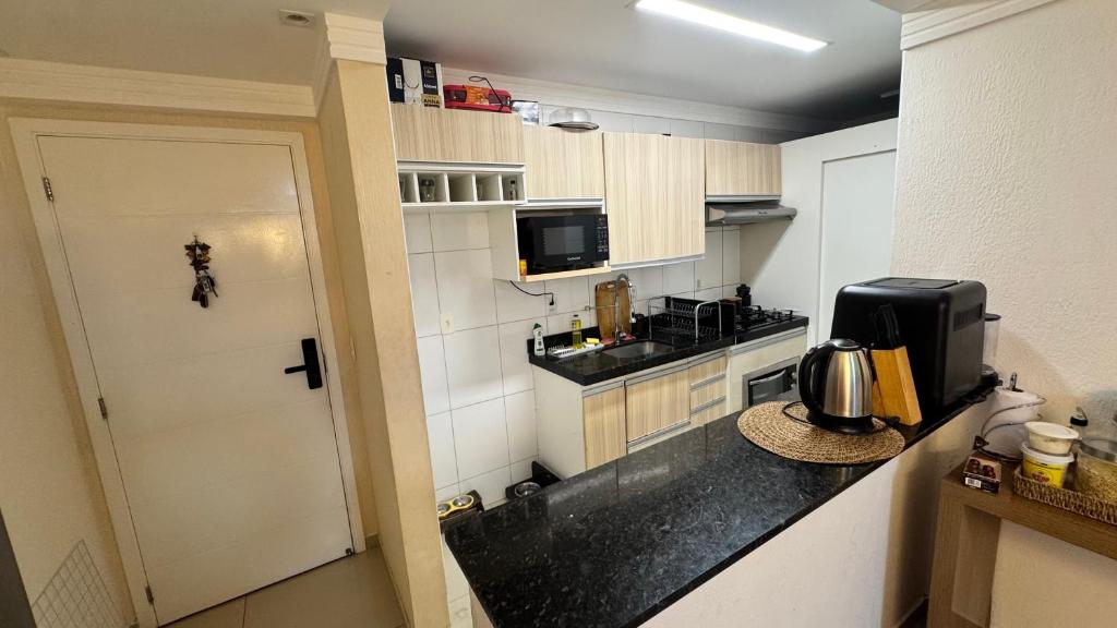 a small kitchen with a counter and a microwave at Quarto em Ap no Renascença in São Luís