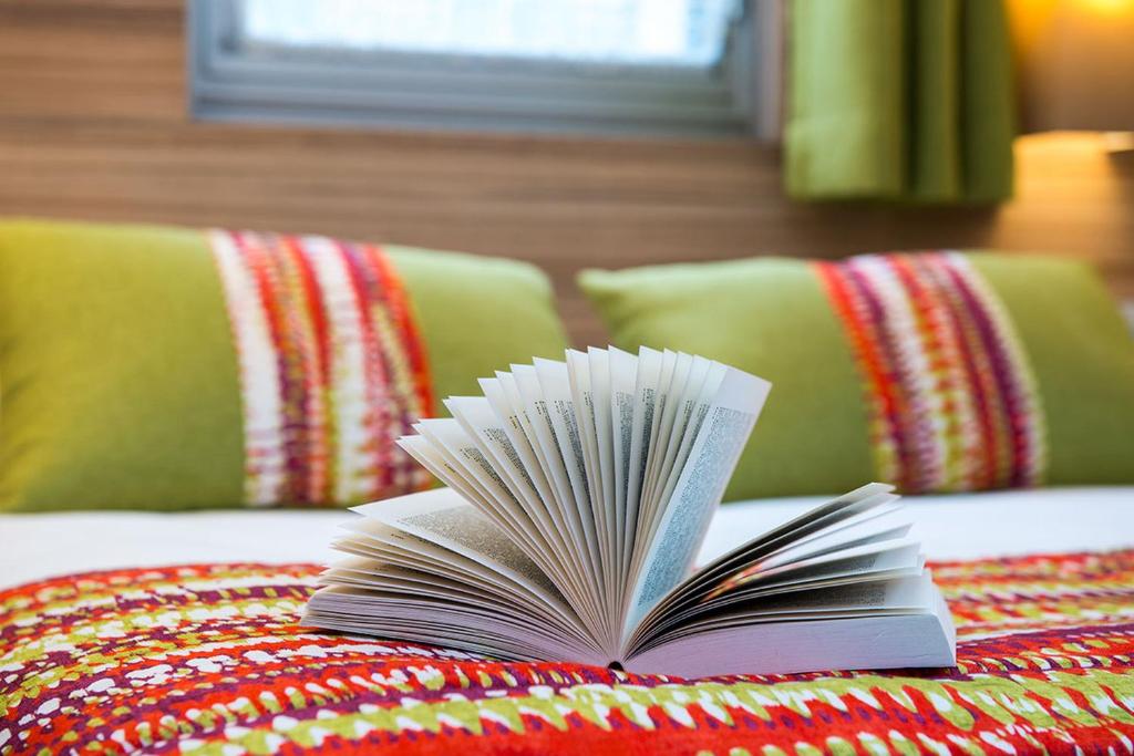 a book sitting on top of a bed at Hôtel Vacances Bleues Delcloy in Saint-Jean-Cap-Ferrat