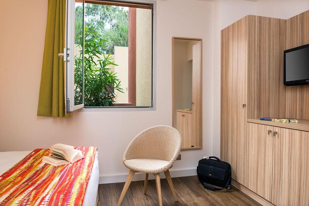 a room with a bed and a chair and a window at Hôtel Vacances Bleues Delcloy in Saint-Jean-Cap-Ferrat