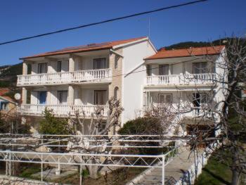 a large white building with a balcony on a hill at Guest House Silvia in Rab