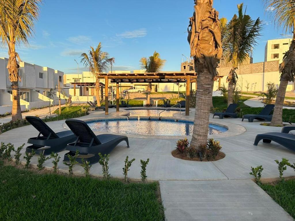 a resort with a pool and chairs and a tree at Casa Las Palmas in Mazatlán